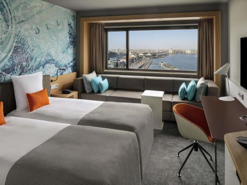 a hotel room with two beds and a window at Mövenpick Hotel Amsterdam City Centre in Amsterdam