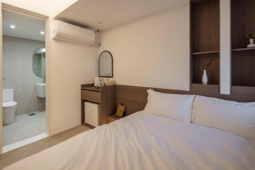 a bedroom with a white bed and a bathroom at YUONJAE Jongno in Seoul