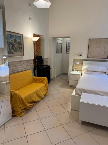 a bedroom with two beds and a yellow chair at Gabici Suite Ravenna in Ravenna