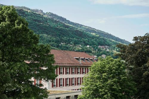 a building with trees in front of a mountain at Le Parc - Hôtel & Spa in Allevard