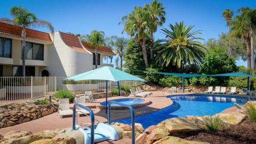 ein Pool mit Sonnenschirmen und Stühlen sowie ein Resort in der Unterkunft Capri Waters Country Club in Mulwala