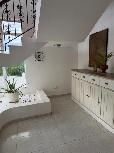 a white kitchen with a staircase and a table at Villa La Dueña in San Felipe de Puerto Plata
