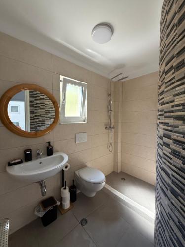 a bathroom with a sink and a toilet and a mirror at Roberts Villa in Dhërmi