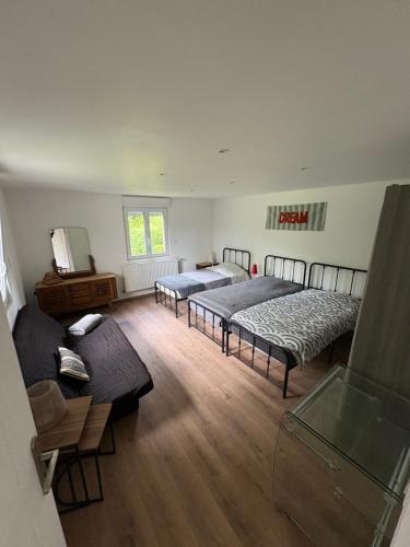 a room with three beds and a couch in it at Le chalet de l Escaut in Bantouzelle