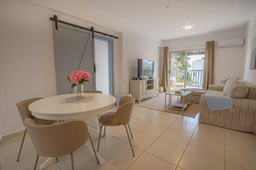 a living room with a table and chairs at Aphrodite Breeze Paphos Gardens in Paphos