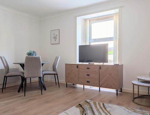 a living room with a tv and a table with chairs at Glentorran in Campbeltown