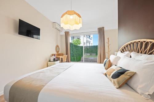 a bedroom with a large white bed and a tv at Hôtel Comté de Nice in Beaulieu-sur-Mer
