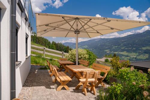 a wooden table and chairs under an umbrella on a patio at Austrian Alpine Apartments in Ramsau am Dachstein