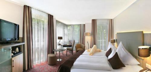 a hotel room with a large bed and a television at Best Western Plus Parkhotel Erding in Erding