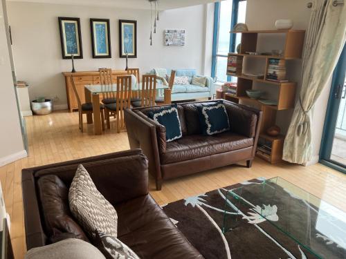 a living room with a couch and a dining room at John's Luxury Seafront Apartment in Newcastle