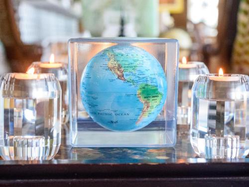 a glass container with a globe and candles on a table at Nakai Beach Homestay in Trafalgar