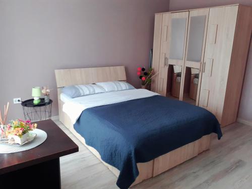 a bedroom with a bed with a blue blanket and a table at Studio Ultracentral cu balcon in Onești