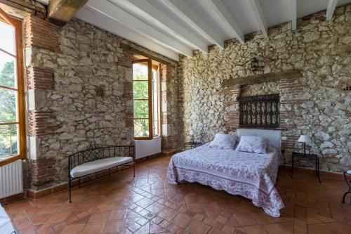 a stone walled bedroom with a bed and windows at La tour du guet in Arouille