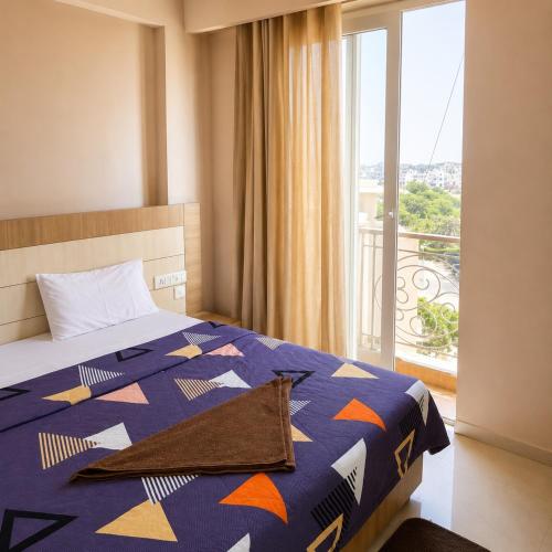 a bedroom with a bed with a blue comforter and a window at Vrindavan Viharini Kunj in Chhatikara
