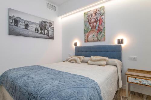 a bedroom with a blue bed and a painting on the wall at Casa Parque Benavente Conil in Conil de la Frontera