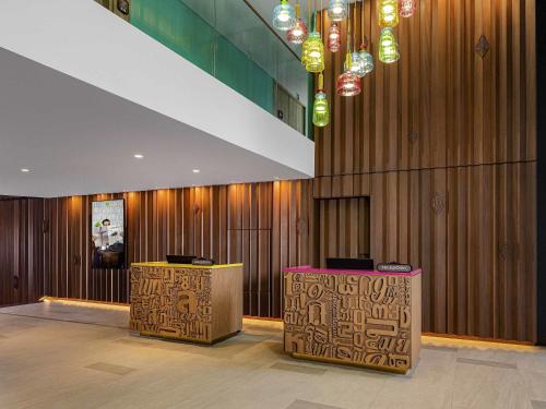 a lobby with two tables and lights on the wall at ibis Styles Bangkok Silom in Bangkok