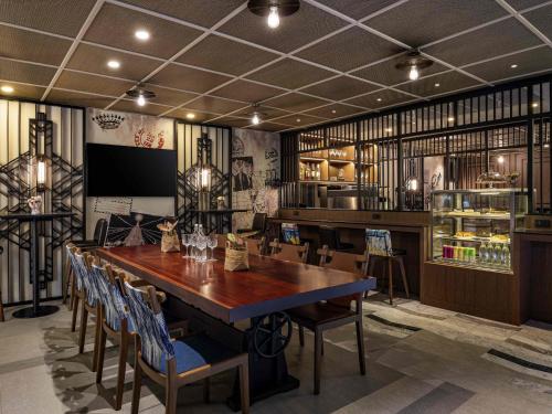 a dining room with a large wooden table and chairs at ibis Styles Bangkok Silom in Bangkok
