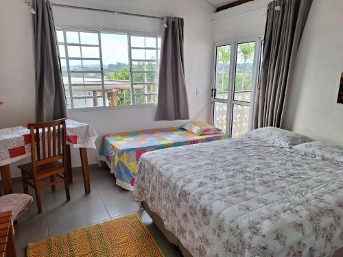 a bedroom with two beds and a table and a window at Pousada Dona Terezinha in Formiga