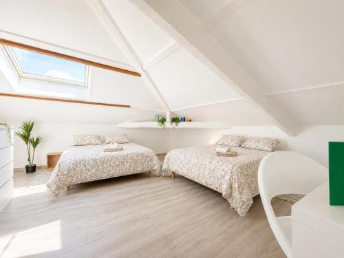 a attic bedroom with two beds and a window at " L'Oratoire Mansardé " Linge fourni - Wifi - TV in Lagardelle-sur-Lèze