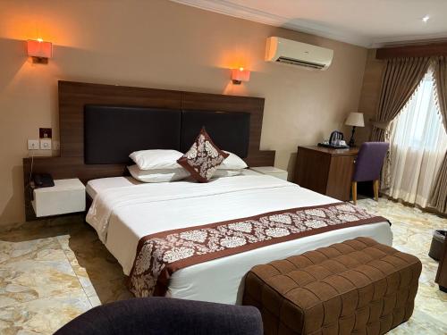 a hotel room with a large bed and a chair at Visa Karena Hotels in Port Harcourt