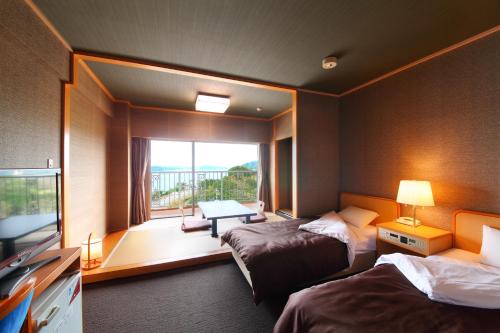 唐津市にある旅宿 よぶこのベッド2台とバルコニーが備わるホテルルームです。