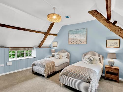 two beds in a room with blue walls at Bobs Cottage Porlock Weir in Porlock