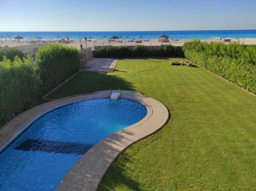 a backyard with a swimming pool and the beach at فيلا غرناطه الساحل الشمالي in Dawwār al Ḩajj Aḩmad