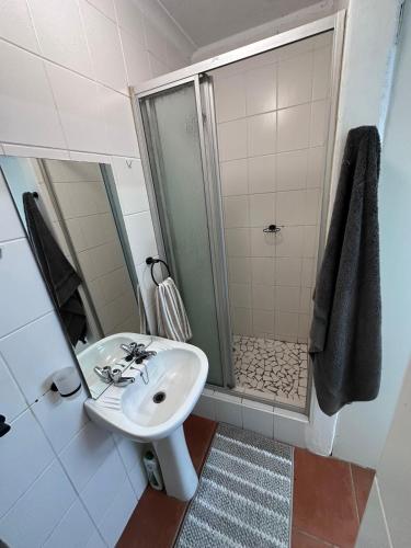 a white bathroom with a shower and a sink at Protea Hoogte Flatlet in Brackenfell