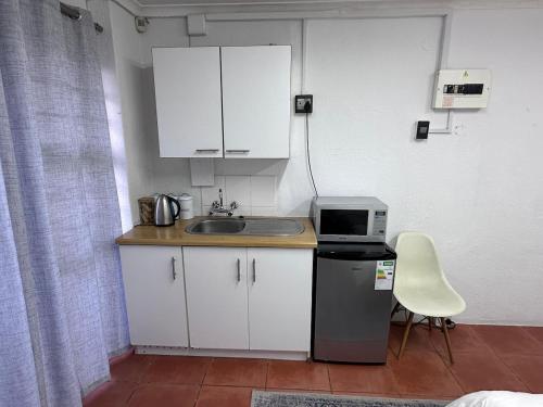 a small kitchen with a sink and a microwave at Protea Hoogte Flatlet in Brackenfell