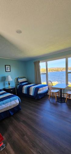 a room with two beds and a table and a window at St Ann's Motel & Cottage in Baddeck