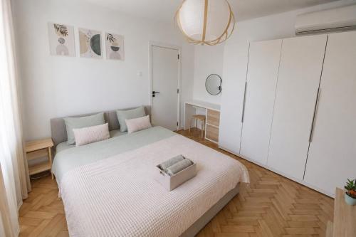 a white bedroom with a bed and a mirror at ZAZA Apartament - central area, with balcony in Târgu Jiu