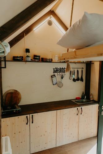 a kitchen with wooden cabinets and utensils on the wall at Glamping Všímarský potok in Malšín