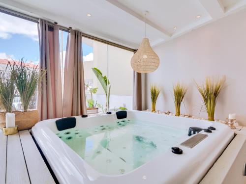 a large bath tub in a room with windows at Villa Monica with Private Pool and Jacuzzi in Quarteira