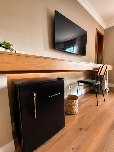 a black refrigerator in a room with a tv on a wall at Pousada Telhado de Ouro in Campos do Jordão