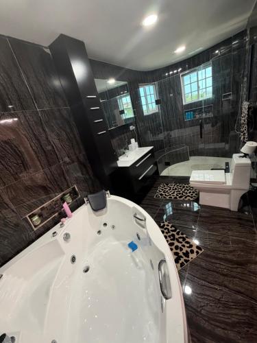 a large bathroom with a tub and a sink at Elysium Noire in Spanish Town