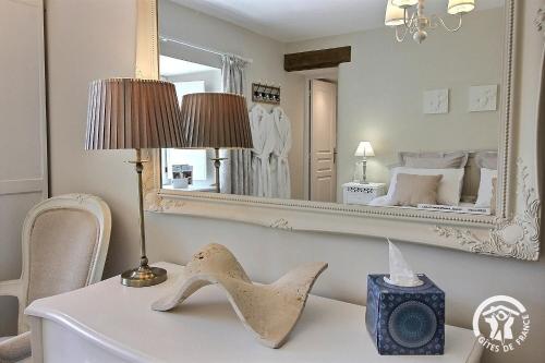 a white table with a lamp and a mirror at Le parfum des fleurs in Plussulien