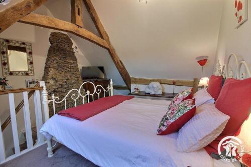 a bedroom with a large white bed with red pillows at Le parfum des fleurs in Plussulien