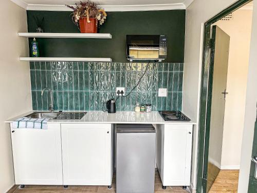 a kitchen with white cabinets and a green wall at Silwood Heights Flatlet in Eerste River in Faure