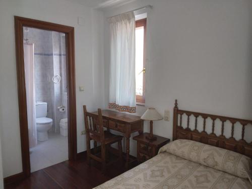 a bedroom with a bed and a desk and a window at Posada San Miguel in RIonansa