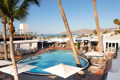 a view of the pool at the resort with palm trees at Plus Fariones Apartamentos in Puerto del Carmen