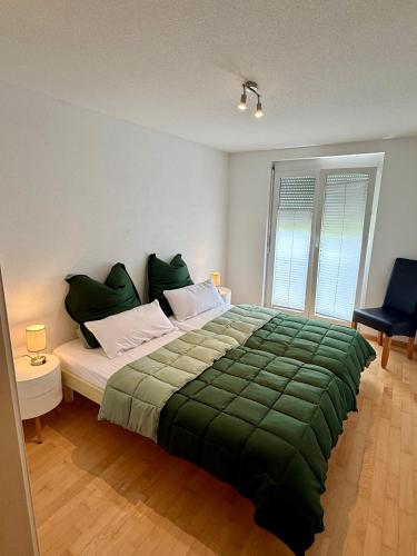 a bedroom with a large bed with a green blanket at Ferienwohnung Bodenseeblick in Hagnau