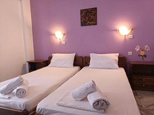 two beds in a room with purple walls at Haras rooms in Nikiana