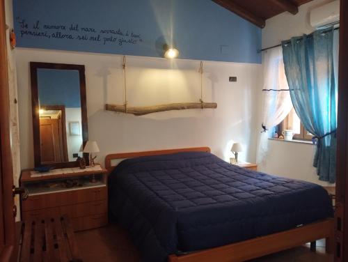 a bedroom with a blue bed and a mirror at La casetta del pescatore - Le case di Bettina in Torrenova