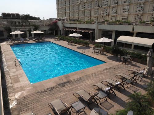 an overhead view of a swimming pool with chairs and umbrellas at Pearl Continental Hotel, Rawalpindi in Rawalpindi