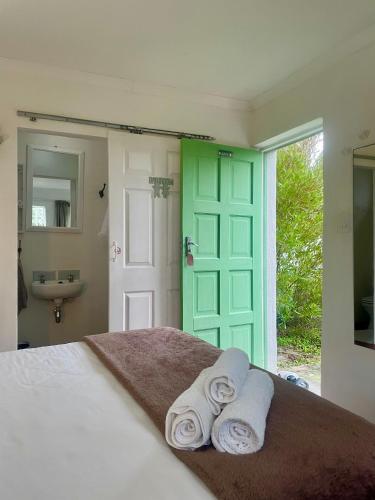 a bedroom with a bed and a green door and towels at Kelp Cottage - Two Private Garden en-suite Rooms in Gansbaai