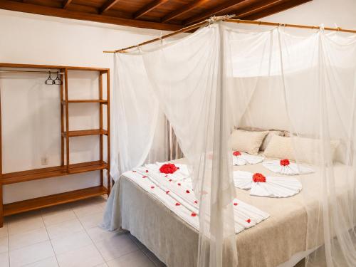 a bedroom with a bed with red flowers on it at Arraial Praia Hotel Pousada in Arraial d'Ajuda