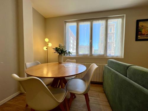 a dining room with a table and chairs and a couch at La Cabine ménage et linge inclus in Dieppe