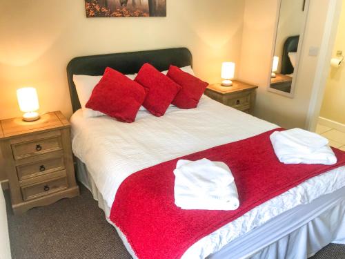 a bedroom with a large bed with red pillows at Brewery Lodge in Blakeney