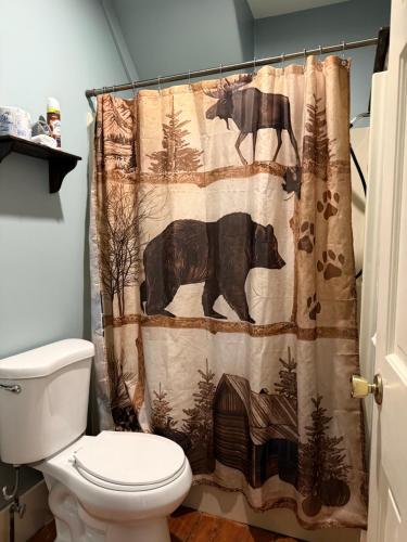 a bathroom with a shower curtain with two animals at Allegory Inn in Twin Mountain
