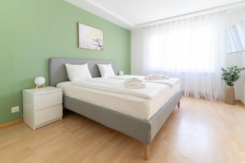 a bedroom with a large bed with green walls at Cozy Swiss Apartment - City & Mountain view in Interlaken